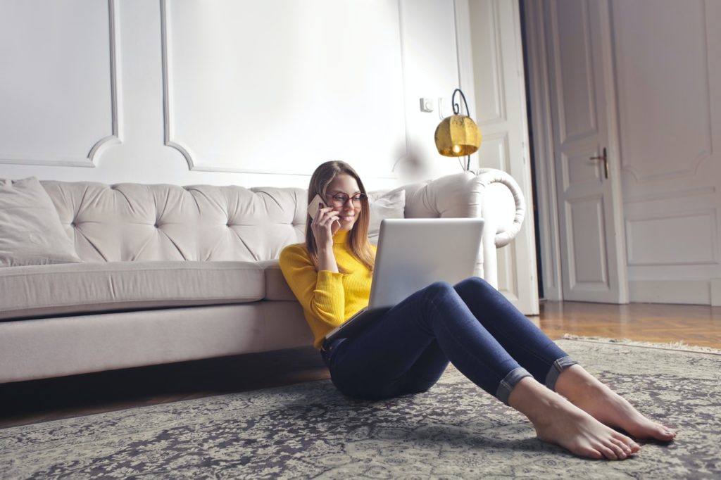 A woman on the phone discusses down payment rates while looking on her laptop.