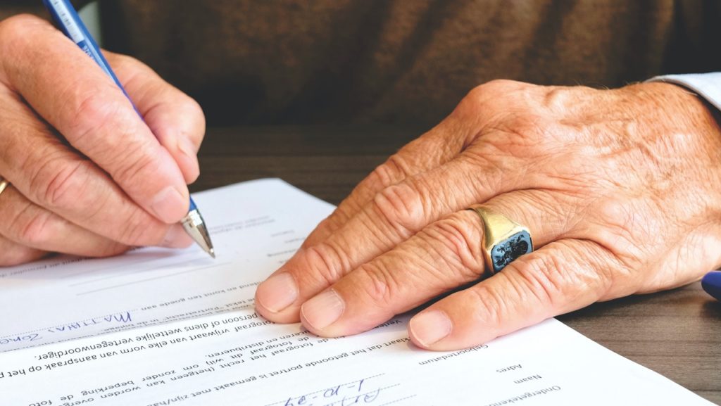 A man signs documents regarding his down payment.