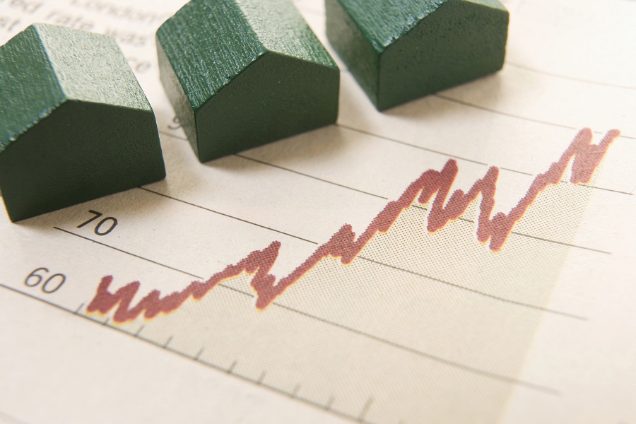 miniature wooden model houses on top of a rising graph