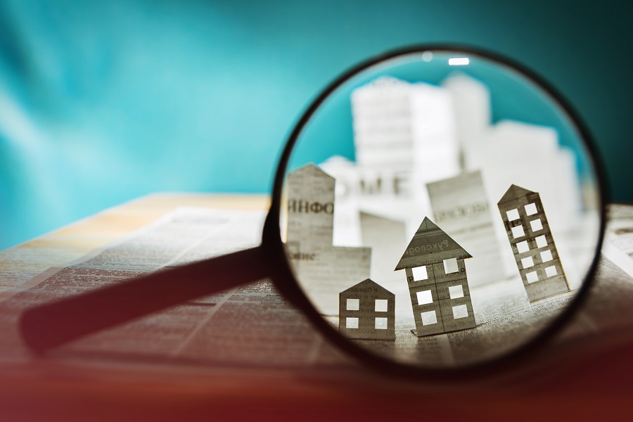 Paper houses magnified in a magnifying glass (inspect the market!)